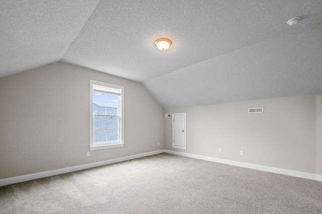 additional living space featuring carpet floors, vaulted ceiling, and a textured ceiling