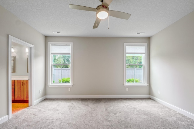 unfurnished room with ceiling fan, light colored carpet, and a textured ceiling