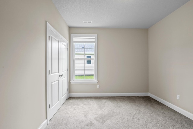 spare room with light carpet and a textured ceiling