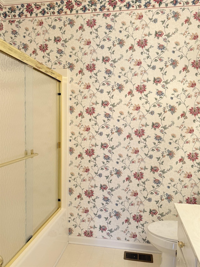 full bathroom with tile patterned flooring, vanity, bath / shower combo with glass door, and toilet