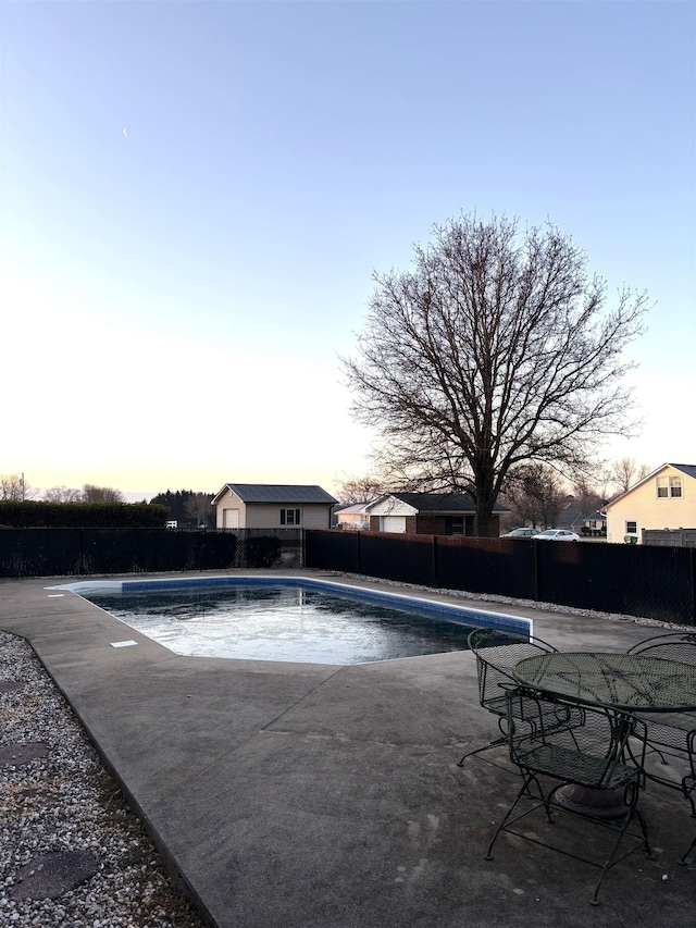 pool at dusk featuring a patio