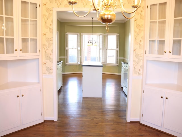 kitchen featuring decorative light fixtures, white cabinets, ornamental molding, a notable chandelier, and dark wood-type flooring