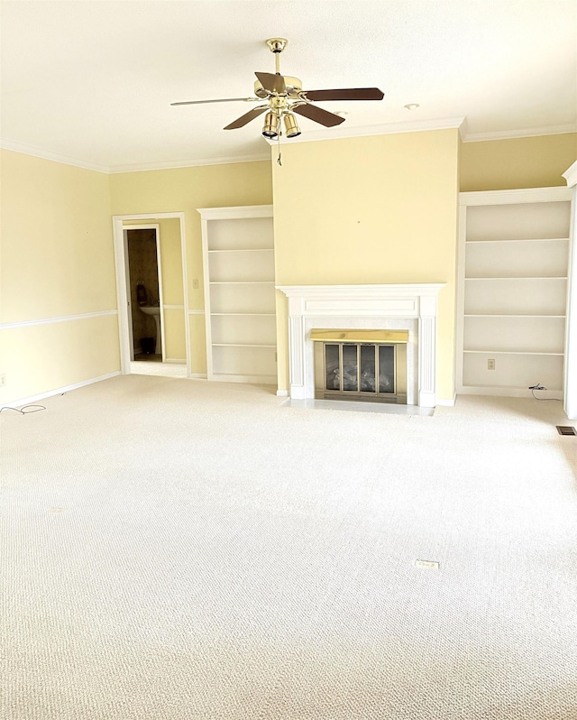 unfurnished living room with built in features, ornamental molding, ceiling fan, and carpet