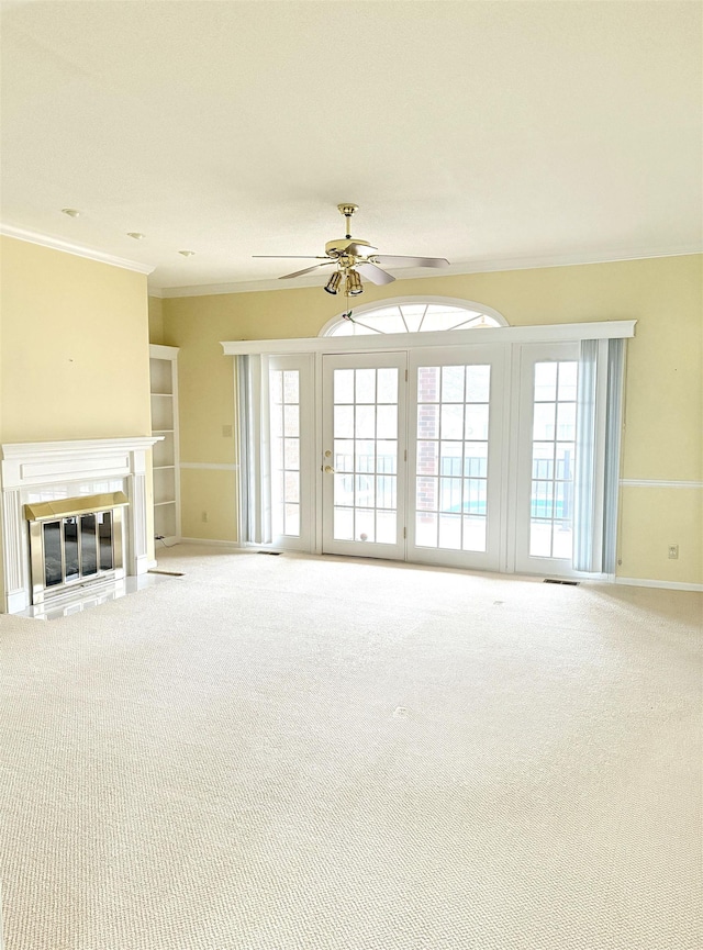 unfurnished living room featuring carpet floors, ornamental molding, and ceiling fan