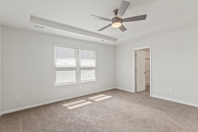 carpeted empty room with a tray ceiling and ceiling fan