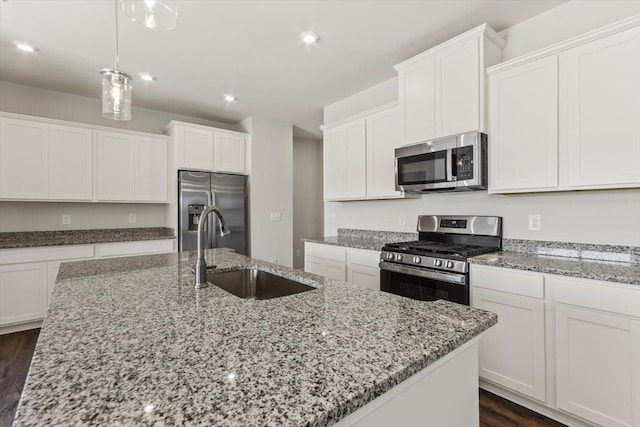 kitchen with stainless steel appliances, sink, white cabinets, and a kitchen island with sink