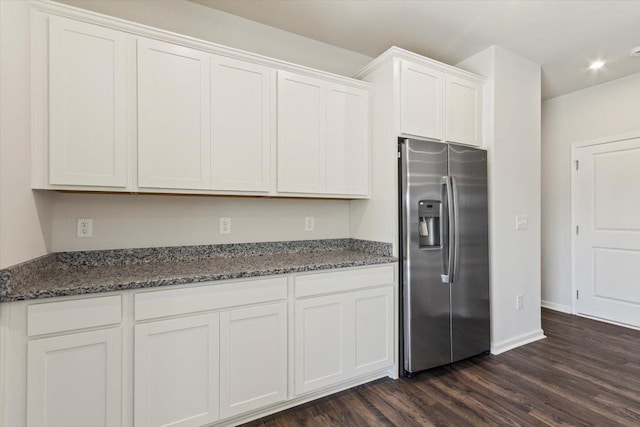 kitchen featuring dark stone countertops, dark hardwood / wood-style flooring, white cabinets, and stainless steel refrigerator with ice dispenser