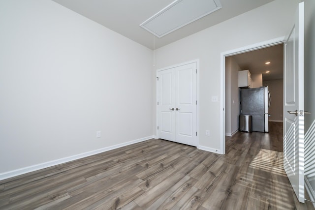 unfurnished bedroom with dark wood-type flooring, stainless steel fridge, and a closet