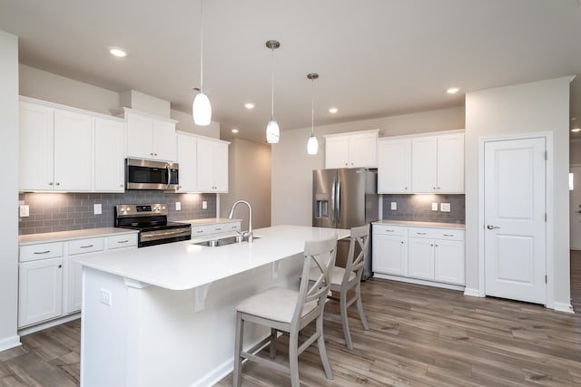 kitchen with stainless steel appliances, sink, white cabinets, and decorative light fixtures