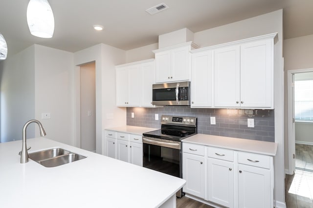 kitchen with appliances with stainless steel finishes, decorative light fixtures, tasteful backsplash, sink, and white cabinets