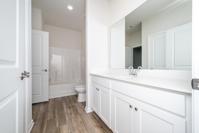 full bathroom with hardwood / wood-style flooring, washtub / shower combination, vanity, and toilet