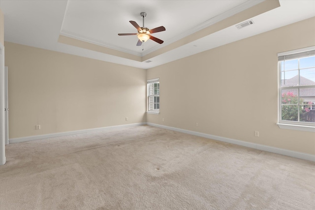 spare room featuring crown molding, light colored carpet, a tray ceiling, and ceiling fan