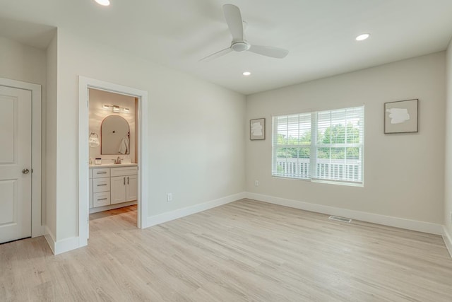 unfurnished bedroom featuring ceiling fan, ensuite bath, and light wood-type flooring