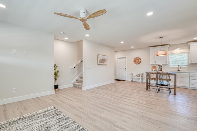 living room featuring sink, ceiling fan, and light wood-type flooring