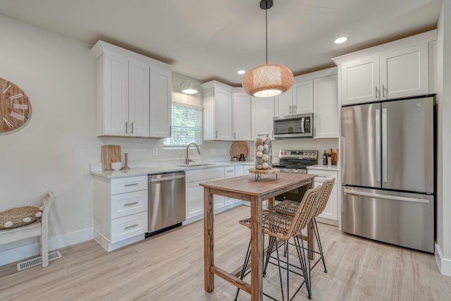 kitchen featuring appliances with stainless steel finishes, sink, white cabinets, and light hardwood / wood-style floors