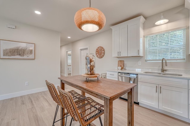 kitchen with sink, decorative light fixtures, light hardwood / wood-style flooring, stainless steel dishwasher, and white cabinets