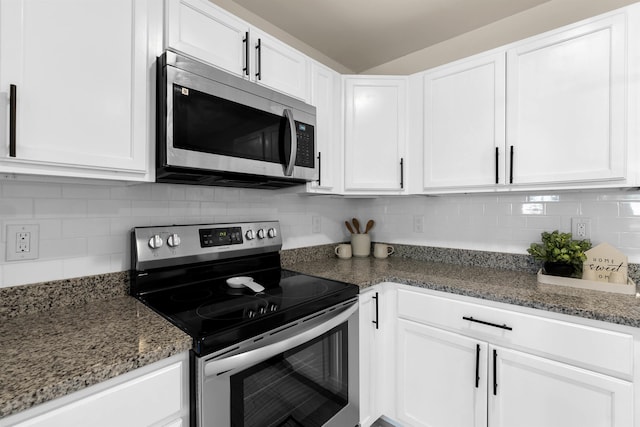 kitchen with tasteful backsplash, stainless steel appliances, dark stone counters, and white cabinets