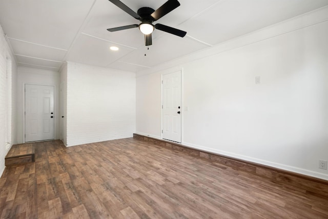 spare room featuring brick wall, hardwood / wood-style floors, and ceiling fan