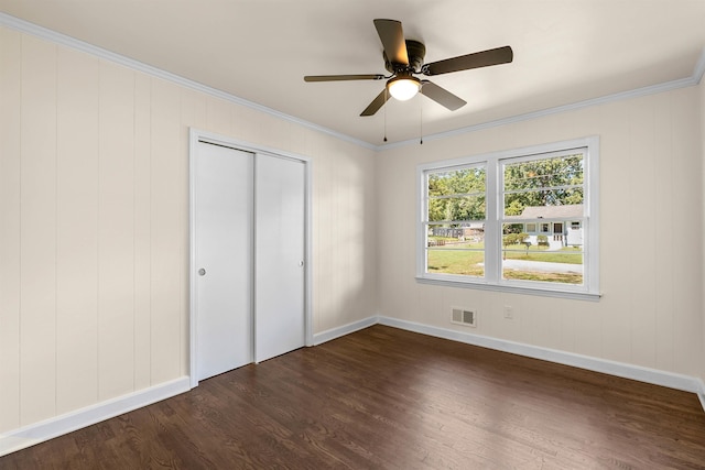 unfurnished bedroom featuring ceiling fan, ornamental molding, dark hardwood / wood-style flooring, and a closet