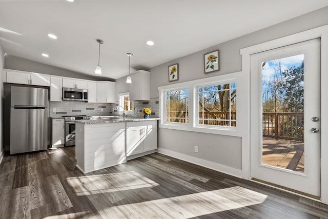 kitchen featuring appliances with stainless steel finishes, pendant lighting, white cabinets, light stone counters, and kitchen peninsula