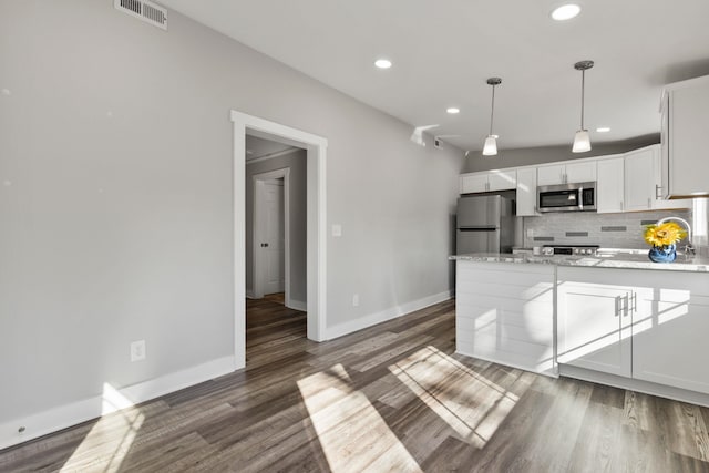 kitchen featuring appliances with stainless steel finishes, white cabinetry, tasteful backsplash, dark hardwood / wood-style flooring, and decorative light fixtures