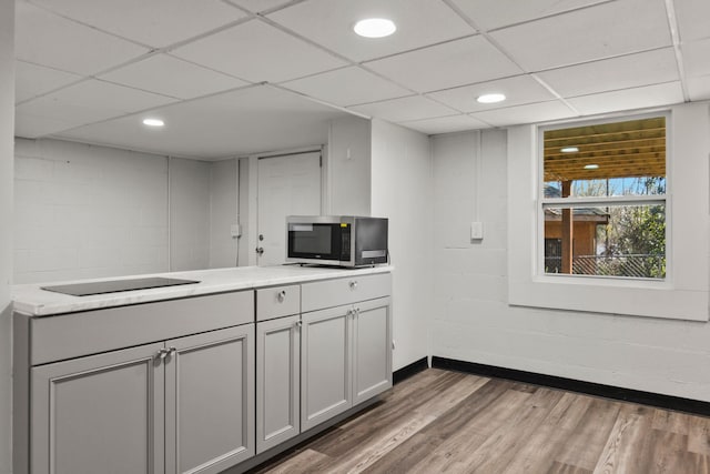 kitchen featuring dark wood-type flooring, black electric stovetop, and a drop ceiling