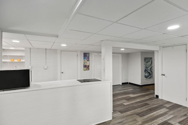 interior space with dark wood-type flooring and a drop ceiling