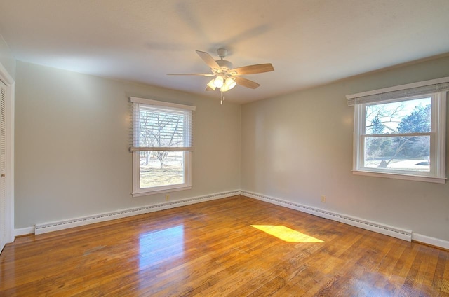 spare room featuring baseboard heating, wood-type flooring, and a wealth of natural light