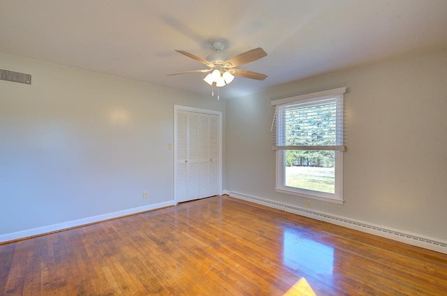 spare room featuring a baseboard heating unit, hardwood / wood-style flooring, and ceiling fan