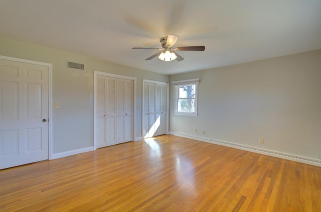 unfurnished bedroom with multiple closets, a baseboard radiator, ceiling fan, and light hardwood / wood-style floors