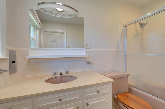 full bathroom with tile walls, vanity, toilet, and combined bath / shower with glass door