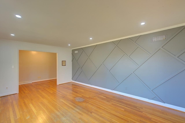 empty room with crown molding and light hardwood / wood-style flooring