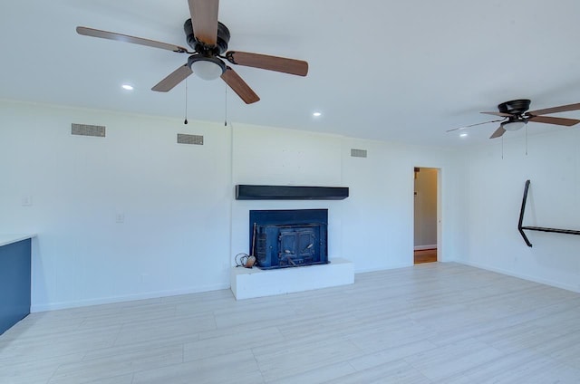 unfurnished living room featuring a large fireplace and ceiling fan