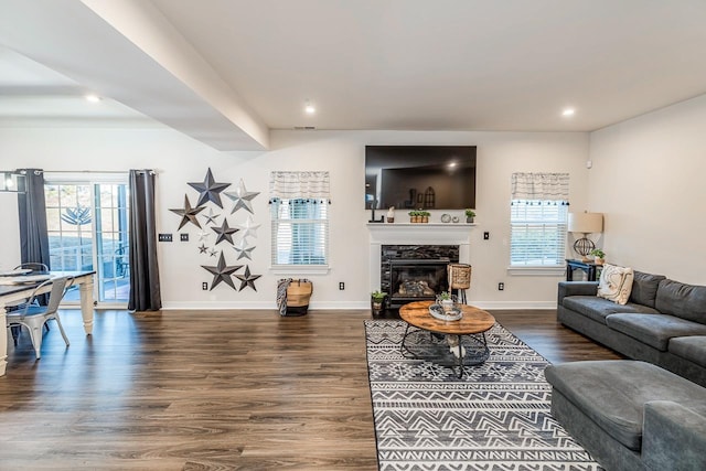 living room featuring dark hardwood / wood-style flooring, plenty of natural light, and a premium fireplace