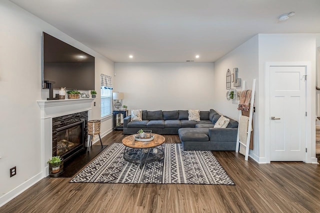 living room featuring a premium fireplace and dark wood-type flooring