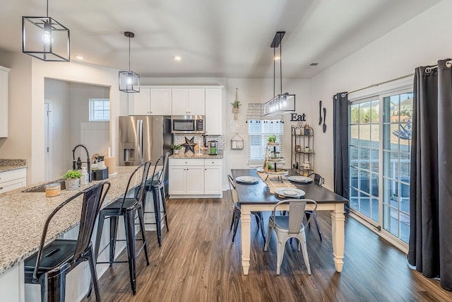 kitchen featuring pendant lighting, sink, white cabinets, stainless steel appliances, and light stone countertops