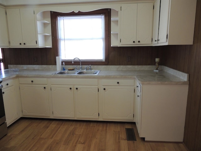 kitchen with sink, white cabinets, and light wood-type flooring