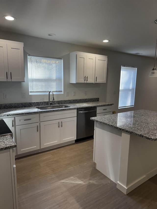 kitchen featuring decorative light fixtures, black dishwasher, sink, and white cabinets