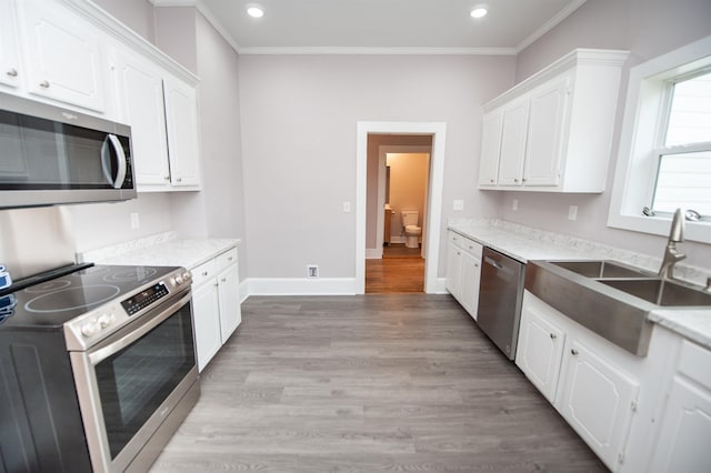 kitchen featuring stainless steel appliances, white cabinetry, sink, and light hardwood / wood-style floors