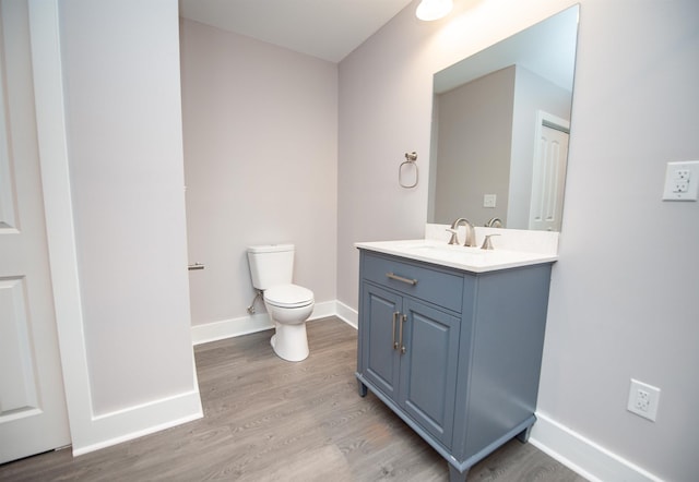 bathroom featuring wood-type flooring, toilet, and vanity