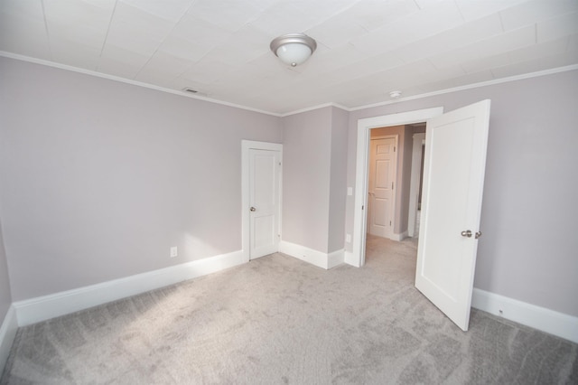 empty room featuring ornamental molding and light carpet