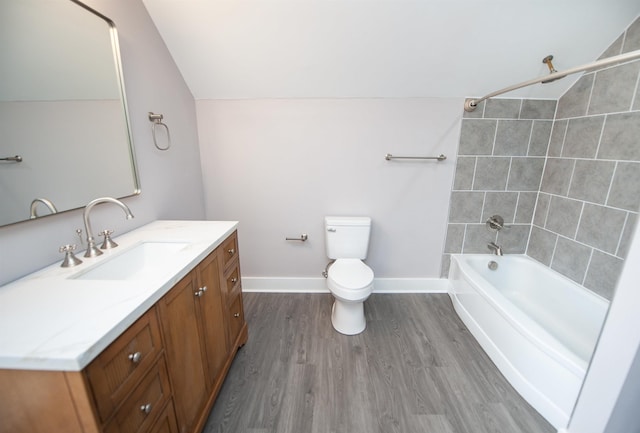 full bathroom with hardwood / wood-style flooring, vanity, vaulted ceiling, toilet, and tiled shower / bath