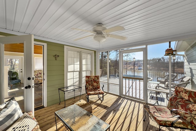 sunroom with a water view and ceiling fan