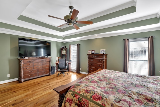 bedroom featuring wood-type flooring, ornamental molding, ceiling fan, and a tray ceiling