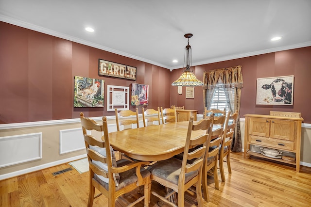 dining space with ornamental molding and light wood-type flooring