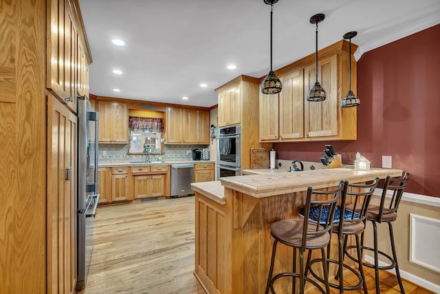 kitchen with a kitchen bar, light hardwood / wood-style flooring, appliances with stainless steel finishes, kitchen peninsula, and decorative backsplash