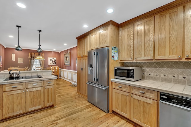 kitchen featuring ornamental molding, appliances with stainless steel finishes, tile counters, and hanging light fixtures