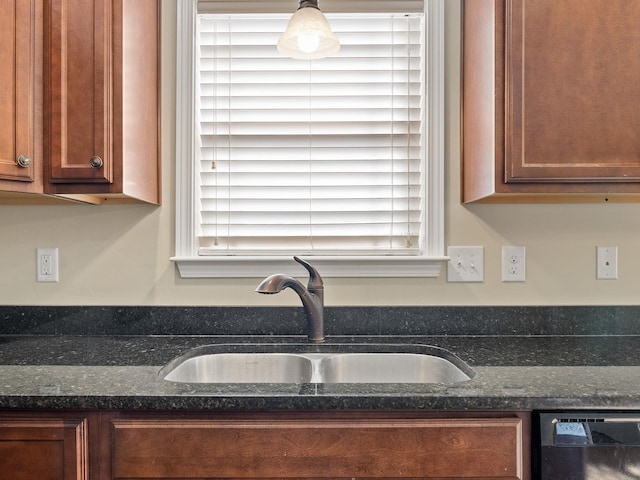 kitchen featuring decorative light fixtures, black dishwasher, sink, and dark stone countertops