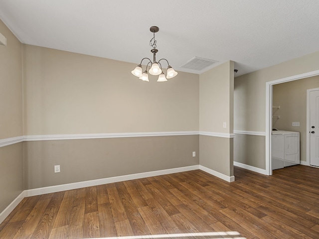 empty room with wood-type flooring, washing machine and clothes dryer, and an inviting chandelier