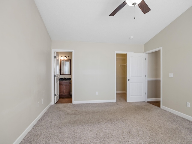 unfurnished bedroom featuring lofted ceiling, carpet, a spacious closet, ensuite bath, and a closet